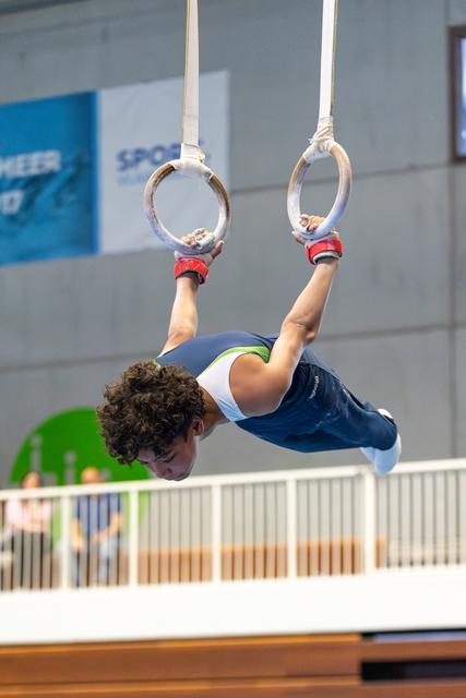 Young athlete performing horizontal hold on gymnastic rings, demonstrating strength and concentration during routine