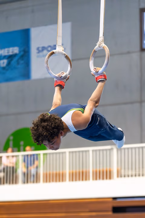 Young athlete performing horizontal hold on gymnastic rings, demonstrating strength and concentration during routine