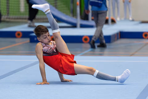 Young athlete performing a side balance during floor routine, demonstrating strength and flexibility at indoor sports facility