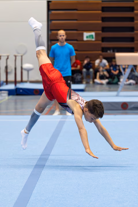 Young athlete executes a dynamic handstand during floor exercise, legs split in mid-air, showcasing flexibility and control