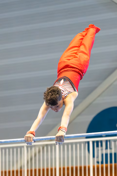 Young athlete performs a handstand on horizontal bar, demonstrating strength and control during routine