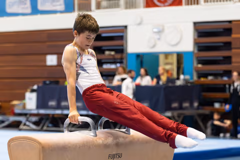 Young gymnast executes a L-sit position on pommel horse, displaying strength and control during training session