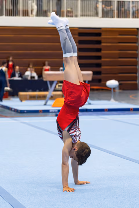 Young athlete performs a handstand on floor exercise mat during indoor training session