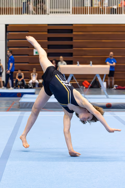 Young athlete mid-cartwheel on floor mat, displaying flexibility and form during routine at indoor sports venue