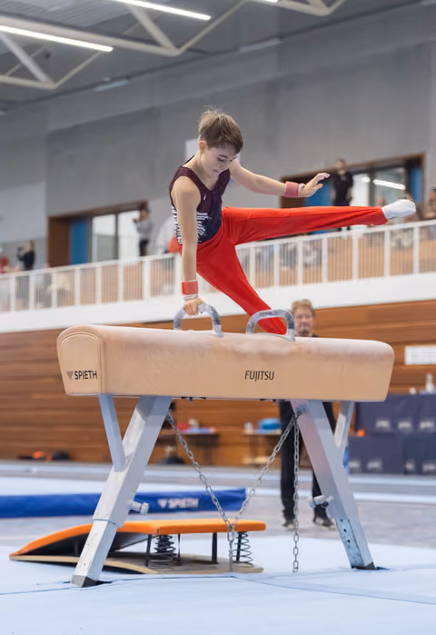 Young gymnast executes a controlled routine on the pommel horse, demonstrating strength and balance in a training facility.