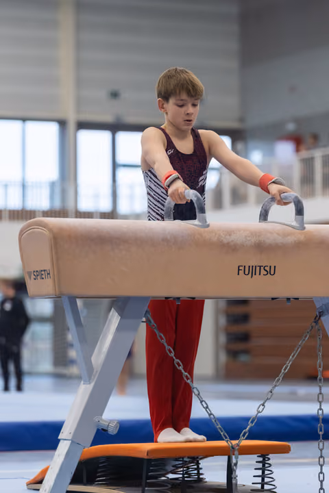Young gymnast gripping pommel horse handles during practice, focused and determined in indoor training facility