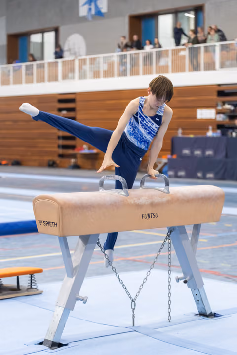 Young gymnast executes a scissor move on pommel horse, legs extended horizontally, displaying strength and control