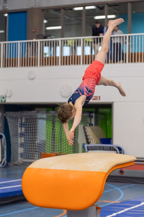 Young gymnast executes a handstand on the vault, demonstrating strength and balance during training at an indoor facility.