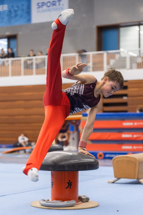 Male gymnast executes a precise handstand position on pommel horse, displaying strength and balance during his routine.
