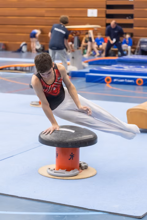 Young gymnast performs a circle drill on mushroom apparatus, extending his body horizontally during practice session
