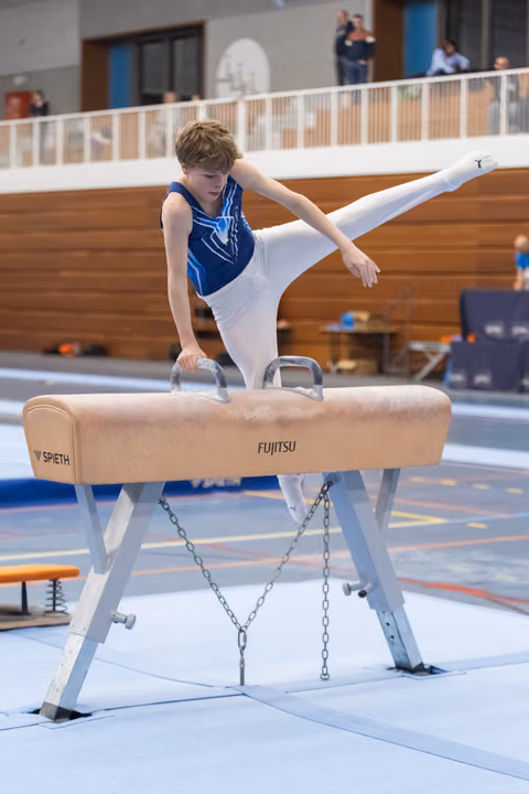 Young gymnast performs side position on pommel horse, leg extended high, white grips visible during training