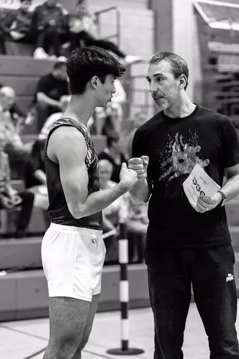 Coach and young boxer shake hands in mutual respect before a match, surrounded by spectators in the arena