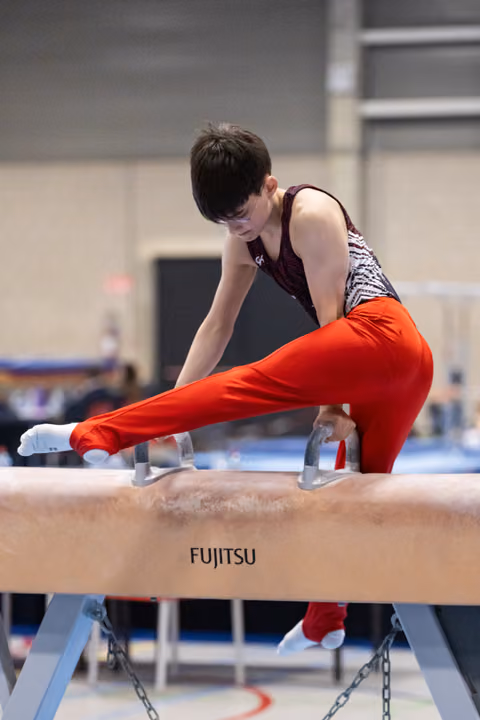 Male gymnast executes a horizontal hold on pommel horse, displaying strength and concentration in competition setting