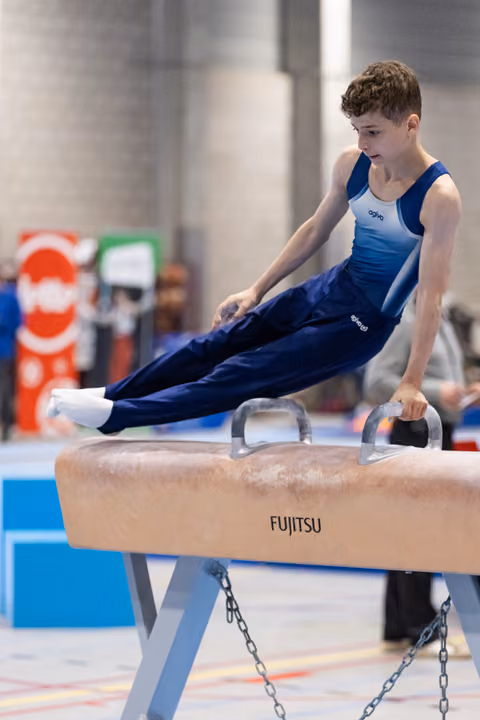 Young male gymnast executes a horizontal support position on pommel horse, displaying strength and concentration
