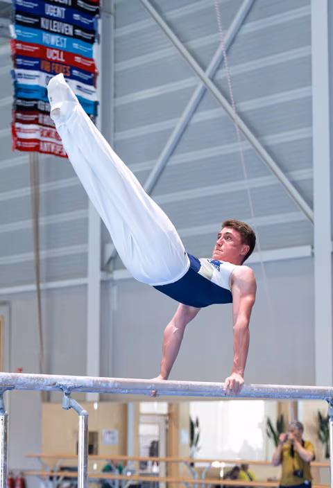 Male gymnast performs impressive L-position strength hold on horizontal bar during training session