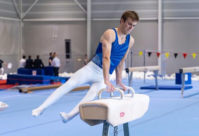 Young male gymnast performing a leg extension on pommel horse during training, demonstrating strength and balance